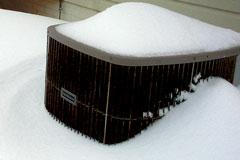 central air conditioning compressor partially covered with snow